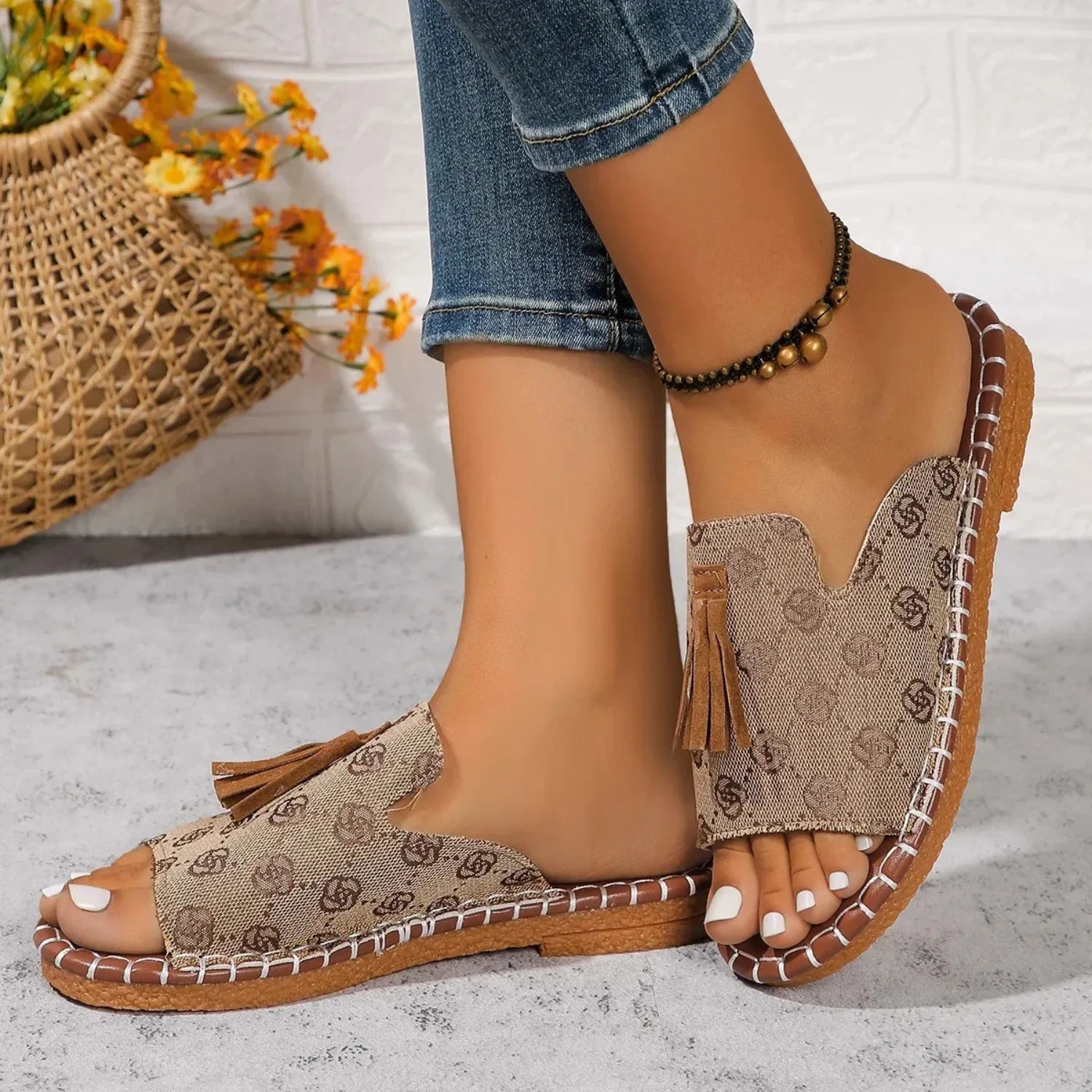 Chinelo slide feminino. O calçado possui uma tira larga com detalhe de borla, ideal para estilo e conforto.