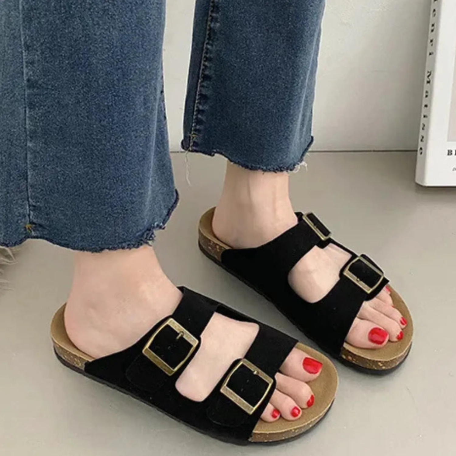 Um par de sandálias de cortiça preta com duas tiras largas, fivelas para ajuste e sola com suporte de arco para máximo conforto.