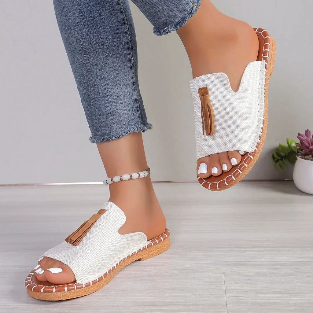 Chinelo slide feminino na cor branca possui uma tira larga com detalhe de borla e uma sola com costura contrastante, ideal para estilo e conforto.