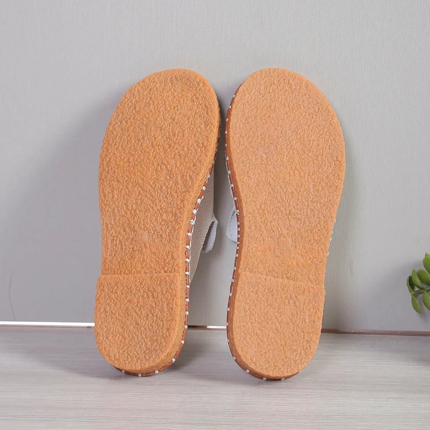 Chinelo slide feminino. O calçado possui uma tira larga com detalhe de borla e uma sola com costura contrastante, ideal para estilo e conforto.
