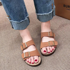 Um par de sandálias de cortiça marrom com tiras largas, fivelas de metal ajustáveis e sola com suporte de arco para máximo conforto.