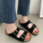 Um par de sandálias de cortiça preta com duas tiras largas, fivelas para ajuste e sola com suporte de arco para máximo conforto.