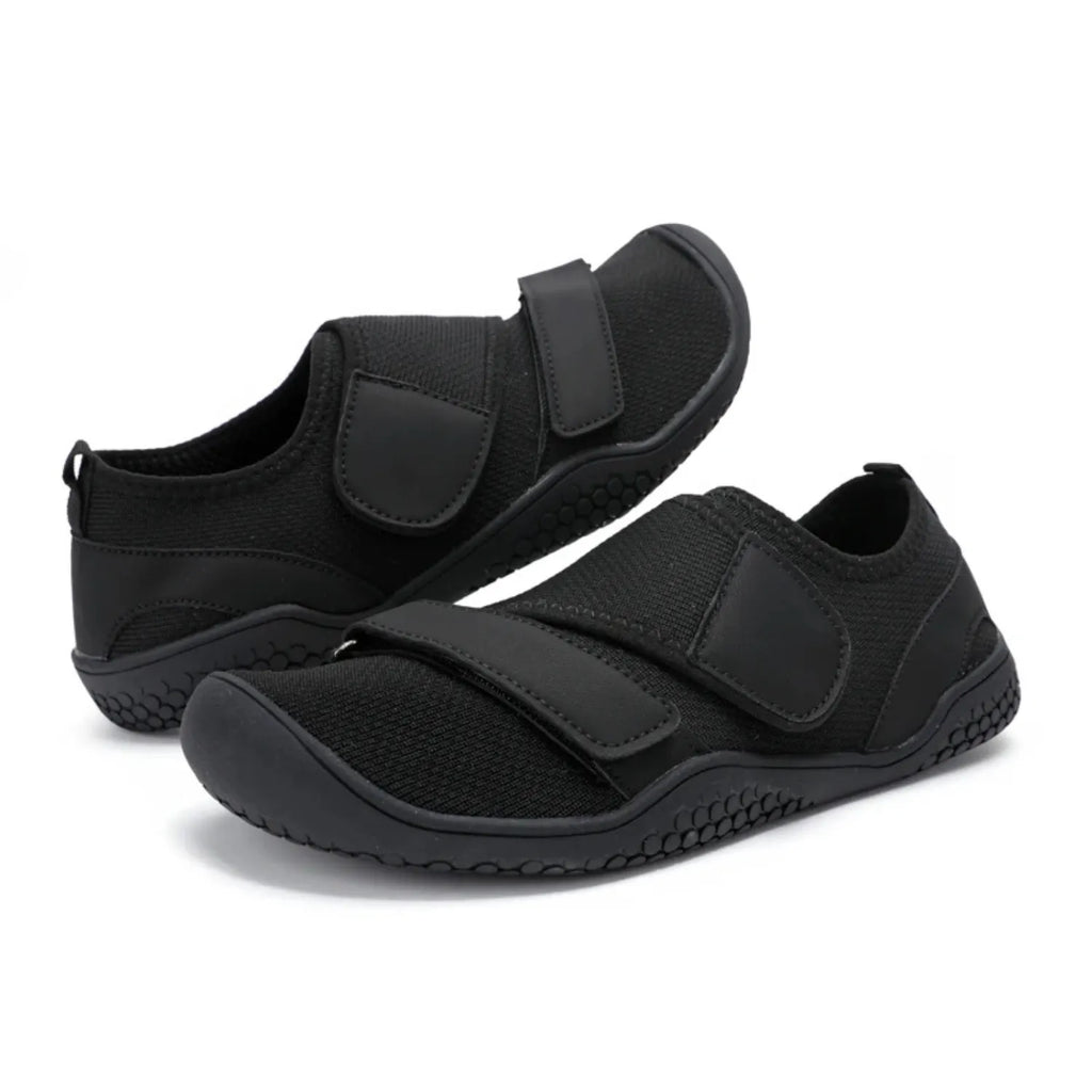 Tênis de treino de força na cor preto com duas fitas de velcro, mostrando o design robusto e a sola plana que proporcionam estabilidade e suporte.