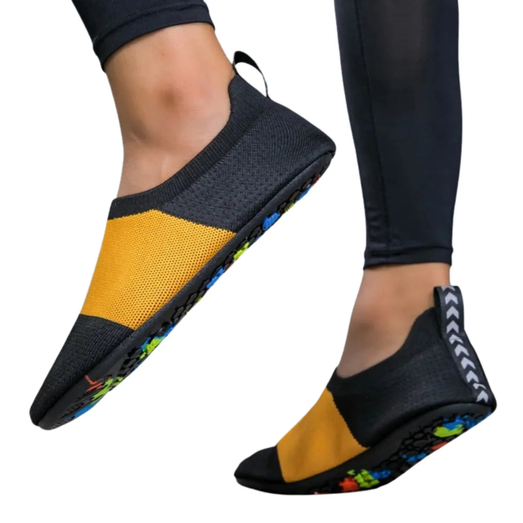 Tênis de yoga unissex preto e amarelo, com design slip-on de tecido flexível tipo meia e sola fina, ideal para exercícios de flexibilidade e proteção.