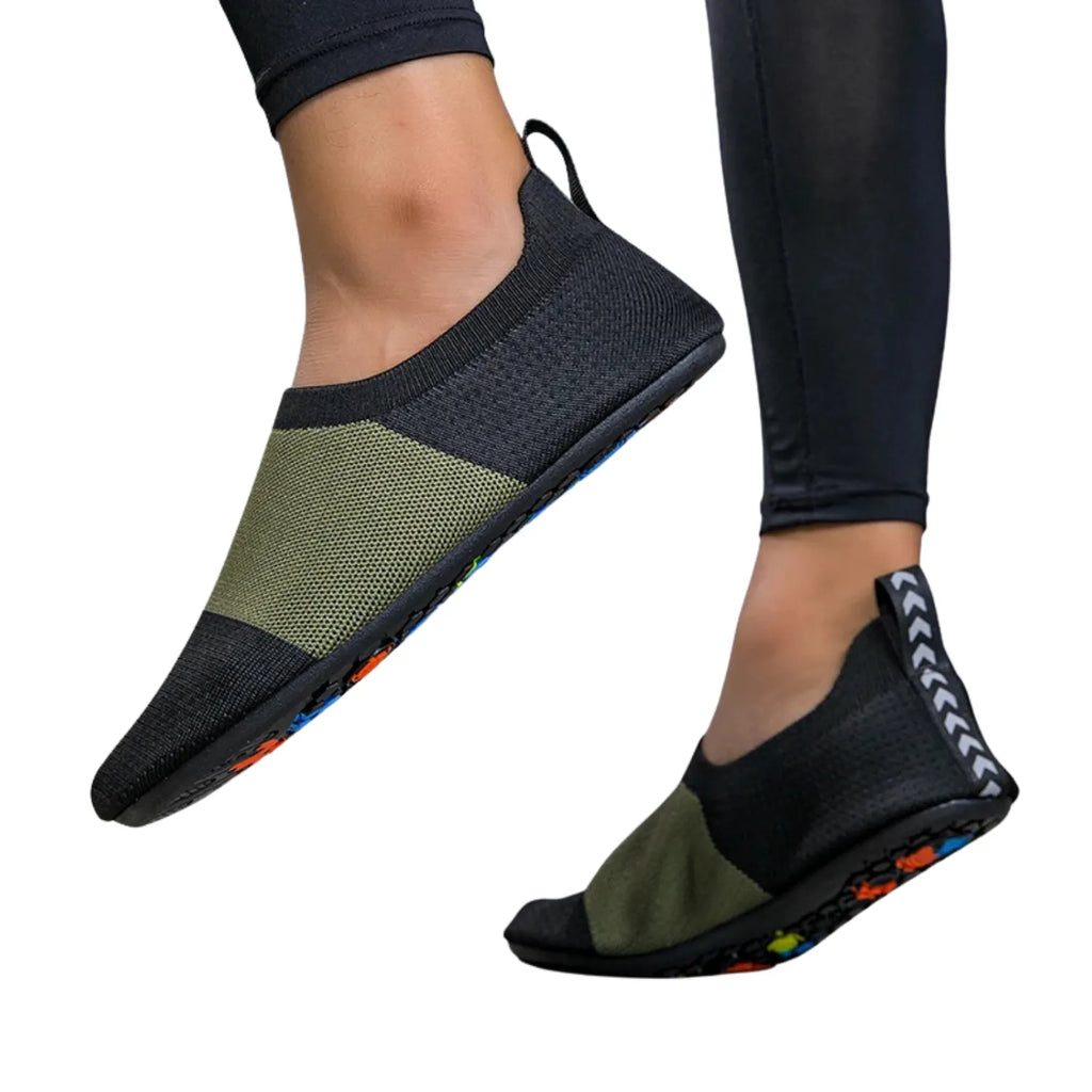 Tênis de yoga unissex preto e verde, com design slip-on de tecido flexível tipo meia e sola fina, ideal para exercícios de flexibilidade e proteção.