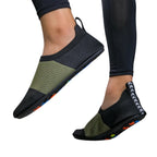 Tênis de yoga unissex preto e verde, com design slip-on de tecido flexível tipo meia e sola fina, ideal para exercícios de flexibilidade e proteção.